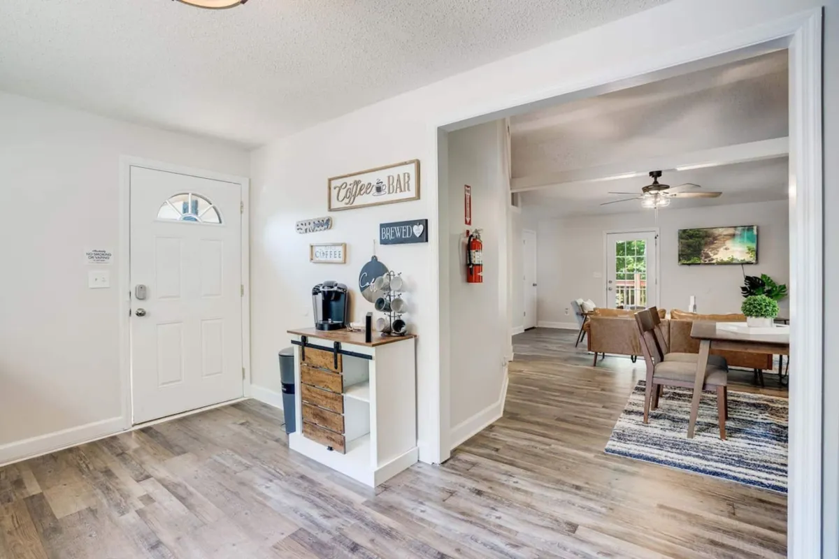 A bright dining area adjacent to the kitchen, featuring a welcoming entrance, a cozy coffee bar, and a table ready for shared meals. The space is designed for both socializing over coffee and enjoying family dinners, highlighted by natural light and inviting decor.