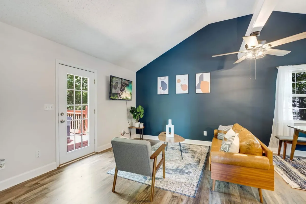 A cozy living room scene featuring a plush sofa, an inviting armchair, a modern coffee table, tasteful wall art, and a window that streams in natural light. The layout encourages relaxation and socializing, with comfortable seating arrangements and warm, homely accents.