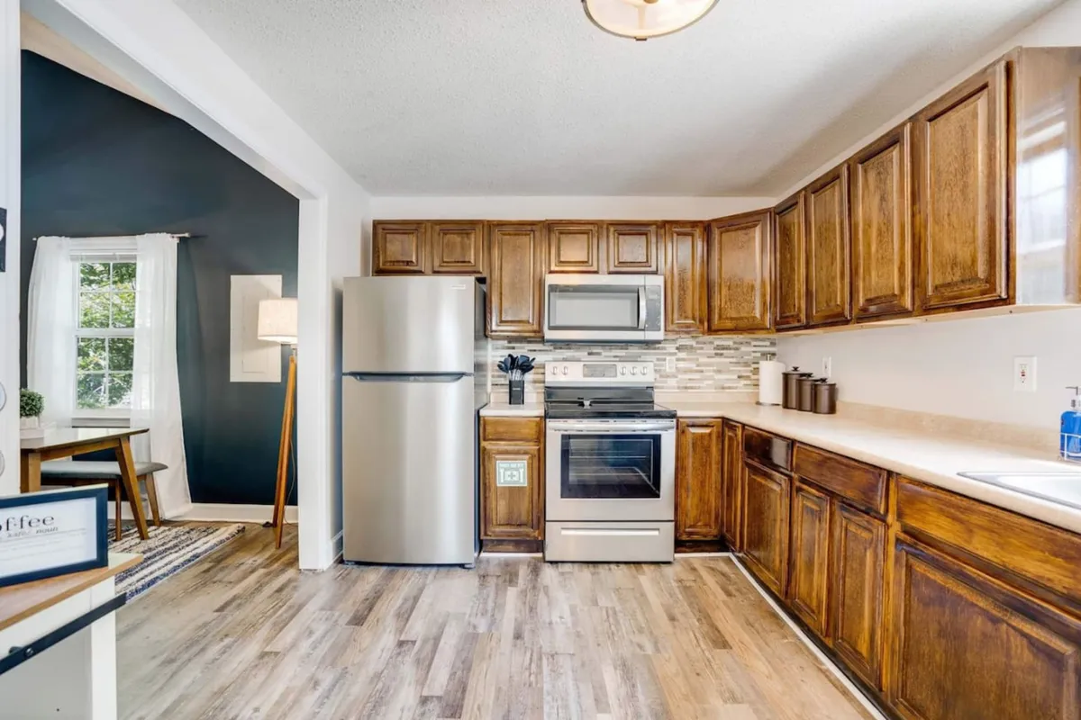A cozy, modern kitchen scene displaying stainless steel appliances, wooden cabinets, a stylish countertop with a subtle backsplash, and a window letting in natural light. The setting is ready for baking, cooking, or gathering for celebrations.